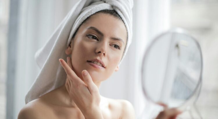 selective focus portrait photo of woman with a towel on head looking in the mirror